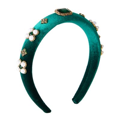 An emerald-green velvet headband embellished with faux emerald and pearl gemstones in shapes reminiscent of Tudor style. 
