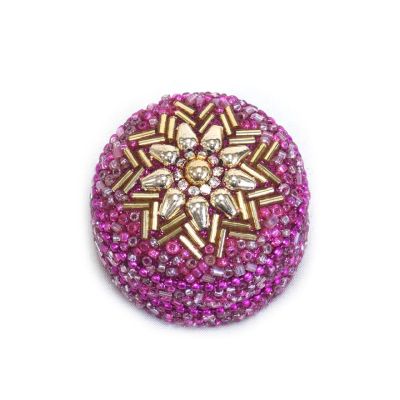 A small pink beaded trinket tin with a gold flower design on the lid. 