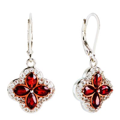 A pair of silver drop earrings with a quatrefoil design inlaid with pear-cut red garnet stones, surrounded by small white topaz stones. 