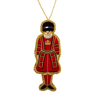 A red and gold embroidered hanging decoration of a Yeoman Warder from the Tower of London. Wearing a black hat and traditional red uniform with a gold crown on the chest. 