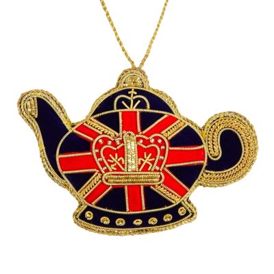 A teapot-shaped hanging decoration in a navy coloured velvet with a red and gold Union Jack design across the middle. In the centre is a gold crown motif made out of gold thread and beads. 