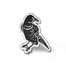 A black metal enamelled pin badge in the shape of a raven. 