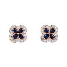 A pair of quatrefoil-shaped silver earrings each with four pear-cut deep blue gemstones with a border of small white topaz stones. 