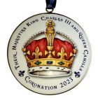 A round, white, metal hanging decoration with a crown illustration in the centre and 'their majesties King Charles III and Queen Camilla coronation 2023' text
