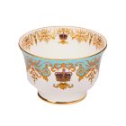 A round, white sugar bowl with a small pedestal base with gold rim details and a blue, gold and burgundy pattern including ornate details and a royal crown. 