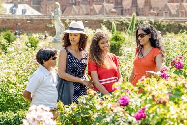 A family of four enjoying a sunny day in Hampton Court Palace gardens.