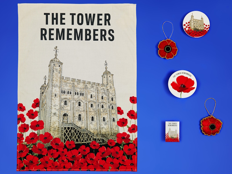 A selection of souvenirs featuring the print of poppies and the White Tower, arranged on a royal blue background.